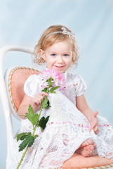 adorable girl sitting on the chair with flower