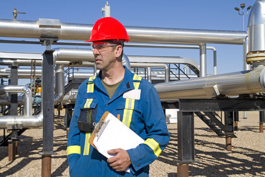 Male gas field operator inspects compressor site