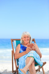 Senior woman reading a book on the beach