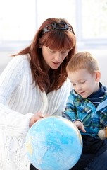 Mother and cute kid studying globe together