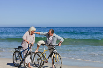 Fototapeta premium Mature couple with their bikes on the beach