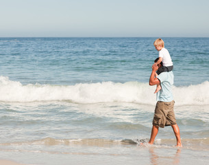 Fototapeta na wymiar Father giving son a piggyback on the beach