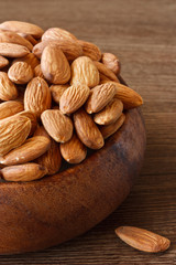 Crude almonds in a brown wooden bowl.