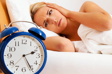 Schlaflos mit Uhr in der Nacht. Frau kann nicht sc