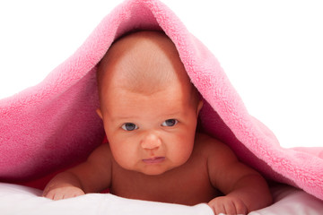 displeased baby girl crawling under a blanket