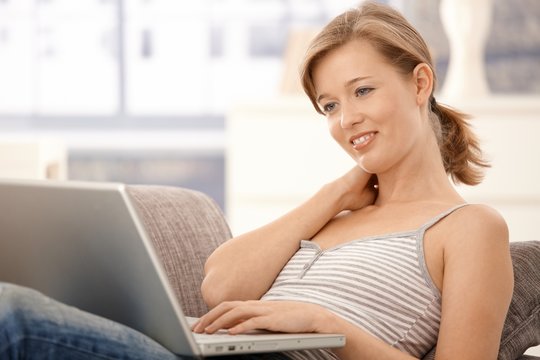Happy young woman browsing internet at home