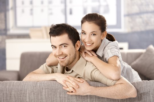 Young couple smiling happily on sofa at home