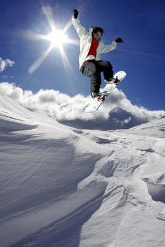Snowboarder jumping against blue sky