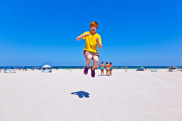 Fototapeta na wymiar happy boy at the beach jumping in the air
