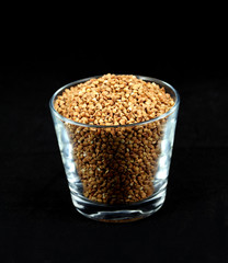 Buckwheat millet kernels in a cup on black background