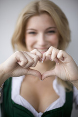 M&auml;dchen im Dirndl formt mit ihren H&auml;nden ein Herz 1