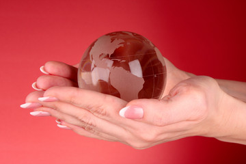 Crystal ball on hand. Red background