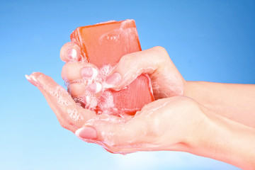 Hands with soap on blue background