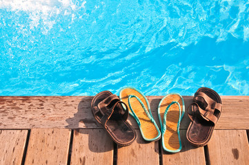 Two pairs (men's and woman's) of flip-flops by swimming pool