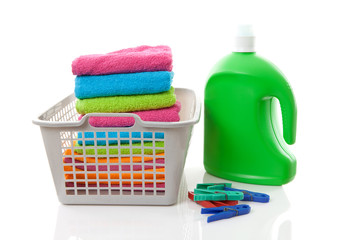 Laundry basket filled with colorful folded towels, pegs and bott