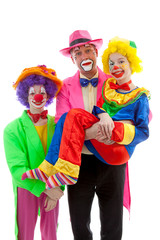 Three people dressed up as colorful funny clowns