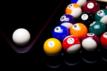 Billiard balls, cue on black table