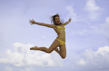 pretty girl in bikini jumping at a hawaii beach