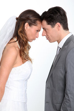 Bride And Groom Standing On White Background With Upset Look