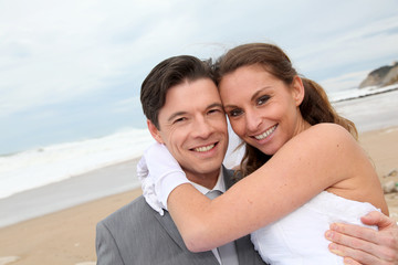 Groom holding bride in his arms at the beach