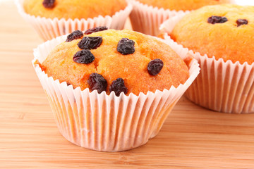 Muffins with raisins on wooden surface