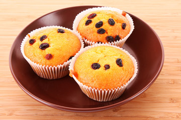 Muffins with raisins on wooden surface