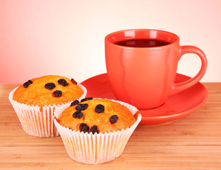 Muffins with raisins and red cup on wooden surface
