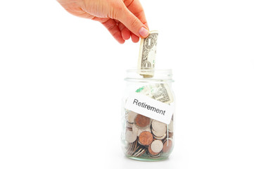 hand putting a dollar into a retirement fund jar