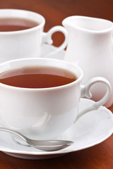 Black tea in mugs with saucers