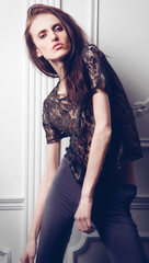 Portrait of the young girl standing at a white wall in studio