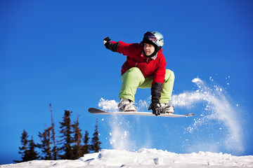 Fototapeta na wymiar Snowboarder jumping through air with blue sky in background