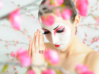 japan geisha woman with creative make-up in sakura garden.close-