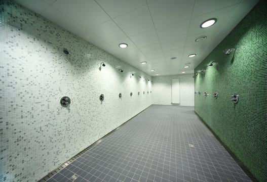 big, light, empty public shower room, green tile on walls