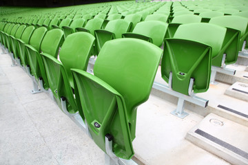 Fototapeta premium Rows of folded, green, plastic seats in very big, empty stadium.