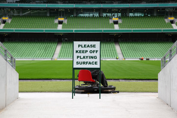 Rijen opgevouwen, groene, plastic stoelen in een heel groot, leeg stadion,