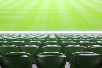 Rijen opgevouwen, groene, plastic stoelen in een heel groot, leeg stadion