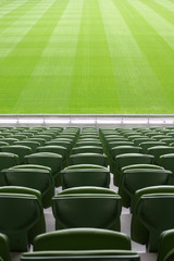 Rijen opgevouwen, groene, plastic stoelen in een heel groot, leeg stadion