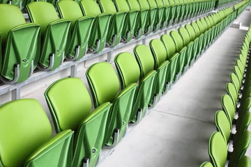 Fotobehang Stadion Rijen opgevouwen, groene, plastic stoelen in een heel groot, leeg stadion