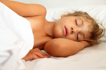beautiful little girl asleep in bed on white sheet and pillow