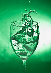 glass with splash on green background