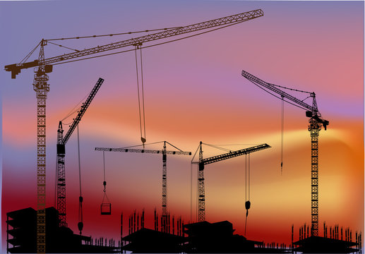 cranes above buildings at sunset