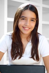 Latin teenager student smiling holding laptop