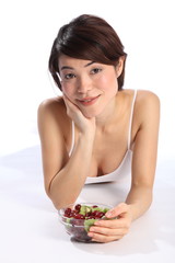 Beautiful woman lying on floor with bowl of fruit