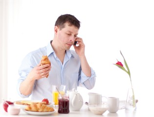 Obraz na płótnie Canvas man speaking on the phone while having breakfast