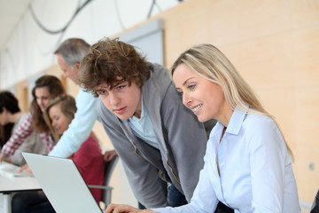 Fototapeta premium Teacher and teenage boy in front of laptop computer