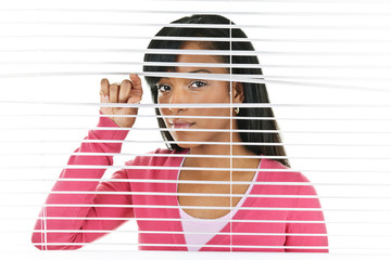 Woman looking through venetian blinds