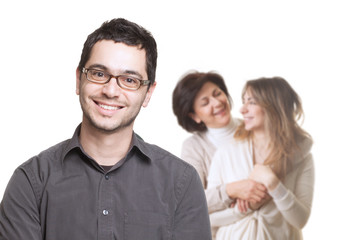 Young man with glasses smiling in front of a young and a middle-