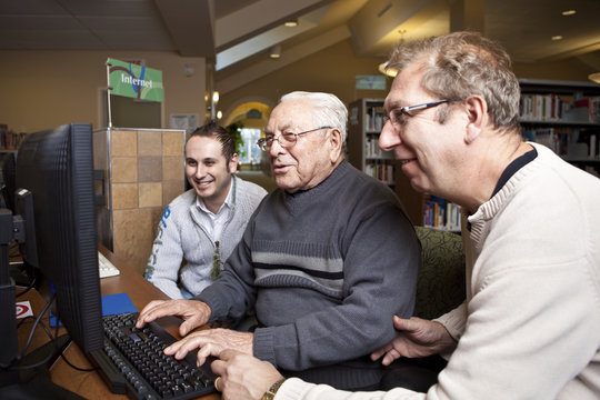 Volunteers teaching a senior how to use a computer