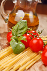 pasta, olive oil and tomatoes on the wood background
