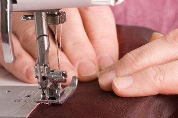 The elderly woman sews on the sewing machine